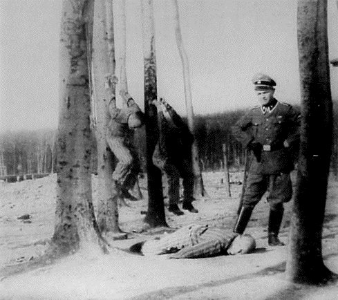 Dead Nazi prisoner watched by soldier, with two other prisoners hanging off trees by the cuffed hands.